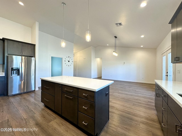 kitchen featuring stainless steel fridge, visible vents, dark wood-style floors, a center island, and light countertops