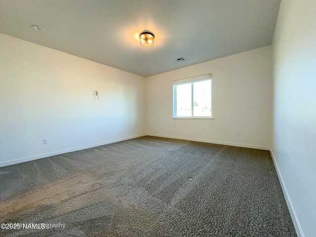 unfurnished room with dark carpet, visible vents, and baseboards