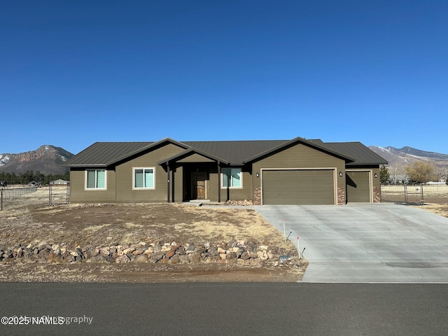 ranch-style house with a garage, driveway, fence, and a mountain view