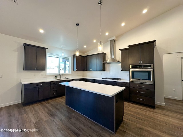 kitchen featuring light countertops, a sink, oven, stovetop, and wall chimney exhaust hood