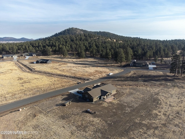 drone / aerial view featuring a wooded view, a rural view, and a mountain view