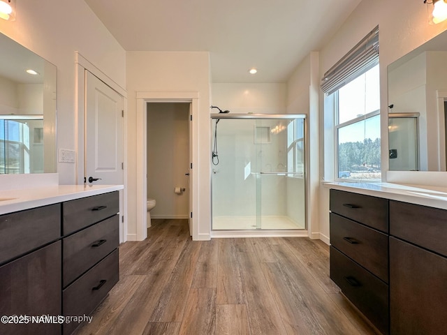 full bathroom with toilet, a stall shower, wood finished floors, and vanity