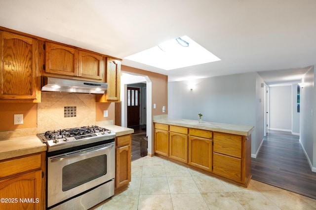 3000 E Matterhorn Dr, Flagstaff, AZ 86004 - kitchen featuring under cabinet range hood, stainless steel gas range oven, brown cabinets, and light countertops