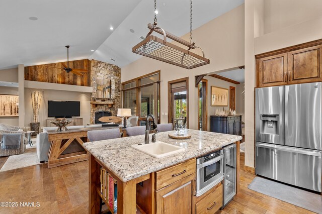 2047 E Del Rae Dr Unit 163, Flagstaff, AZ 86005 - kitchen featuring stainless steel refrigerator with ice dispenser, light wood-style floors, a fireplace, high vaulted ceiling, and light stone countertops