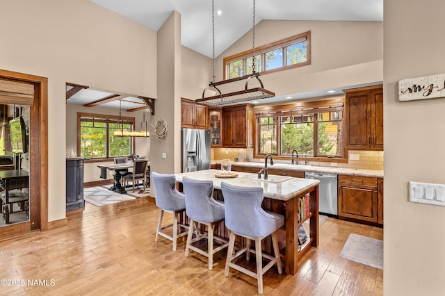 2047 E Del Rae Dr Unit 163, Flagstaff, AZ 86005 - kitchen featuring stainless steel appliances, high vaulted ceiling, a kitchen breakfast bar, light stone counters, and an island with sink