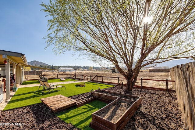 view of yard featuring a mountain view, a fenced backyard, and a garden