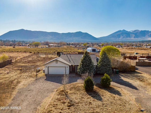 view of front of property featuring a mountain view, driveway, an attached garage, fence, and a shingled roof