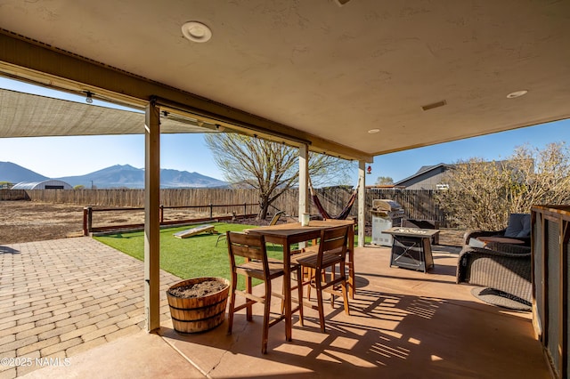 view of patio featuring a mountain view, a fenced backyard, and a fire pit