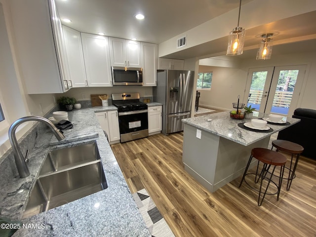 1024 E Hillcrest Dr, Flagstaff, AZ 86004 - kitchen with appliances with stainless steel finishes, a sink, light wood-type flooring, light stone countertops, and white cabinetry