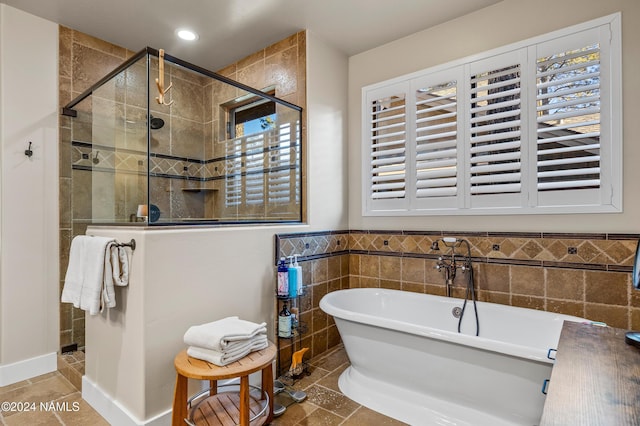 bathroom with separate shower and tub, a wealth of natural light, and tile walls