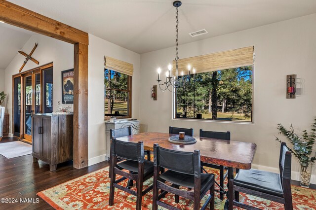 dining room with dark wood-type flooring, vaulted ceiling, and an inviting chandelier