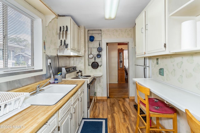 kitchen featuring sink, a healthy amount of sunlight, white cabinetry, and electric range oven