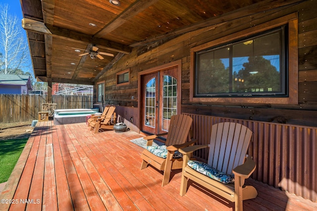 deck featuring ceiling fan, fence, a covered hot tub, and french doors