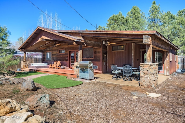 rear view of house featuring ceiling fan, a deck, fence, and a hot tub