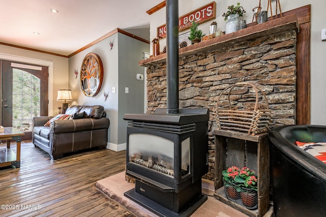 living area with a wood stove, wood-type flooring, ornamental molding, and baseboards