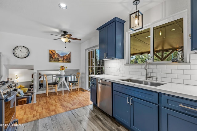 kitchen with blue cabinetry, hanging light fixtures, dark hardwood / wood-style flooring, sink, and stainless steel dishwasher