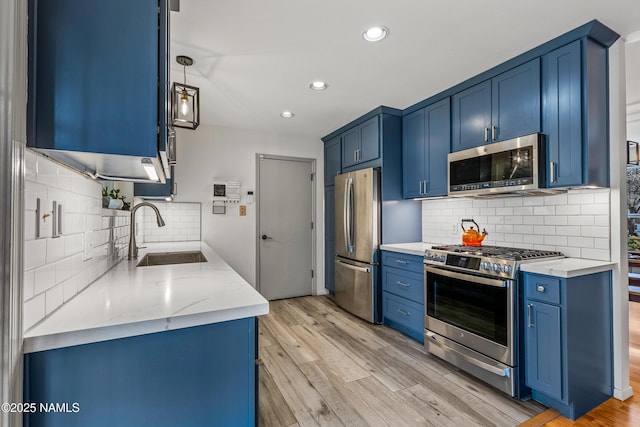 kitchen with appliances with stainless steel finishes, sink, blue cabinets, and light wood-type flooring