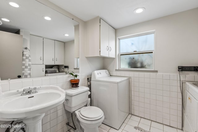 bathroom with sink, tile walls, washer / dryer, toilet, and tile patterned floors