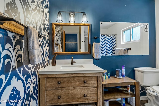 bathroom with toilet, vanity, and baseboards