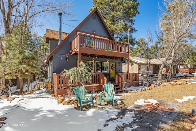 snow covered property featuring stucco siding and a deck