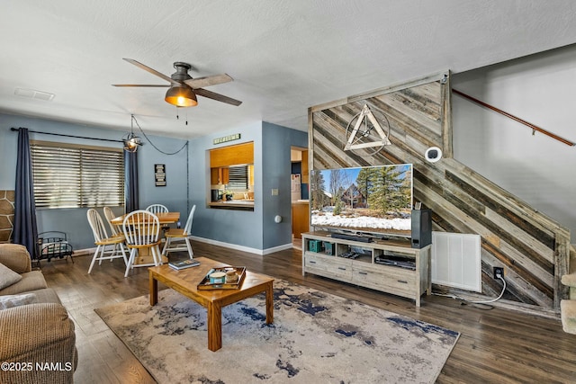 living area featuring baseboards, a textured ceiling, ceiling fan, and hardwood / wood-style flooring