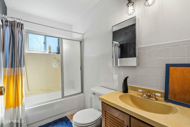 bathroom featuring vanity, tile walls, toilet, and combined bath / shower with glass door