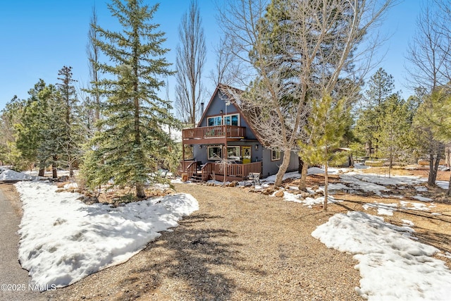 snow covered rear of property with a wooden deck