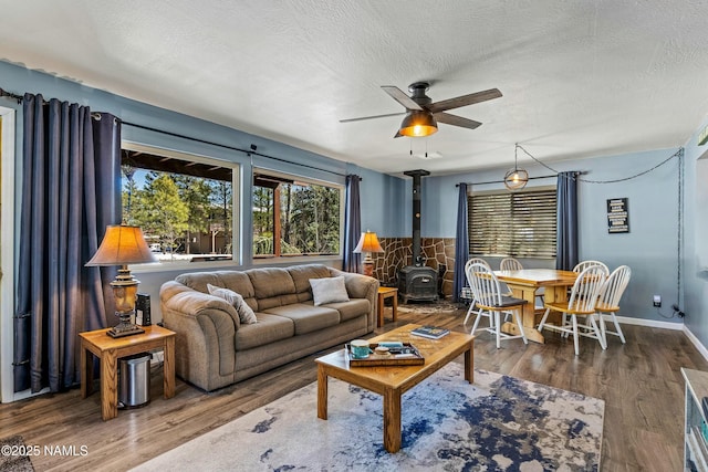 living area featuring a textured ceiling, wood finished floors, and a wood stove