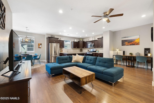 living room featuring recessed lighting, baseboards, wood finished floors, and ceiling fan with notable chandelier
