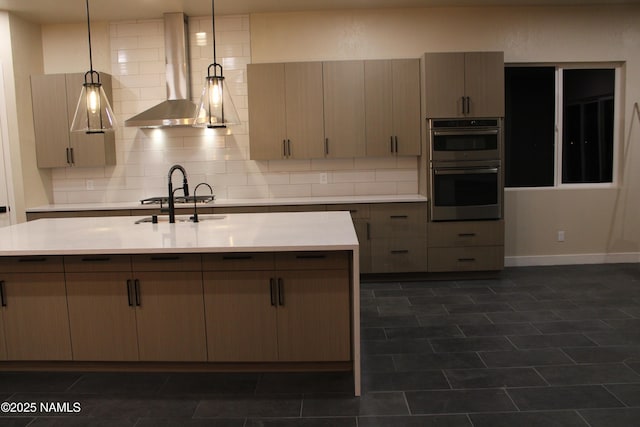 kitchen with backsplash, appliances with stainless steel finishes, decorative light fixtures, and wall chimney range hood