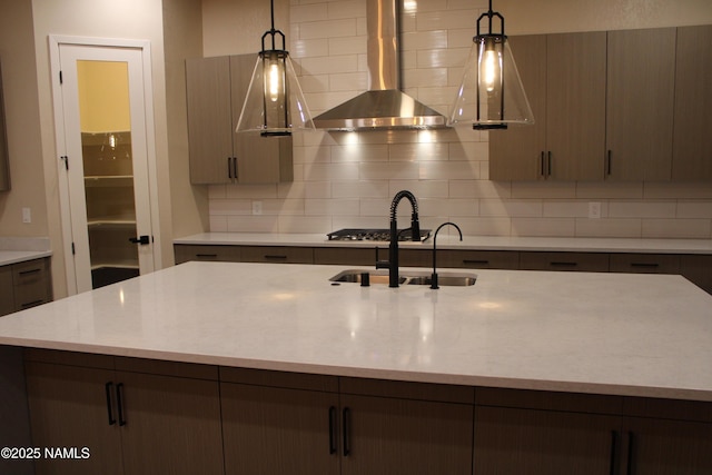 kitchen featuring backsplash, decorative light fixtures, and wall chimney exhaust hood