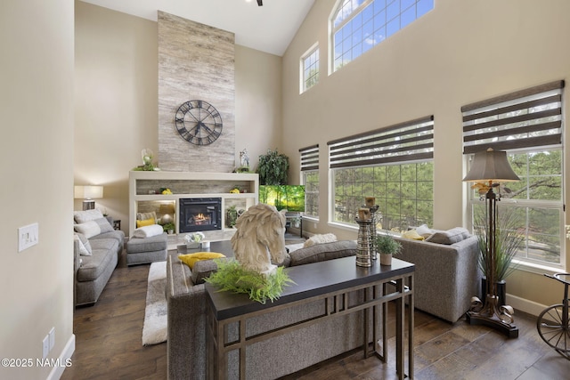 1248 W Lil Ben Trl, Flagstaff, AZ 86001 - living area featuring dark wood-style floors, a towering ceiling, a tiled fireplace, and baseboards