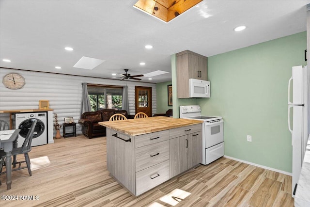 kitchen with white appliances, washer / clothes dryer, a skylight, rustic walls, and light hardwood / wood-style flooring