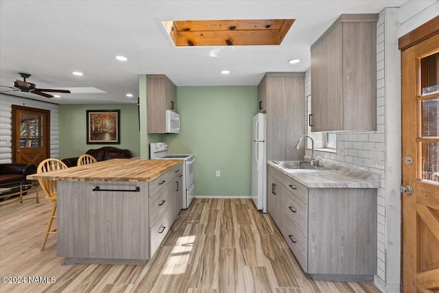 kitchen with white appliances, tasteful backsplash, a kitchen breakfast bar, sink, and light hardwood / wood-style flooring