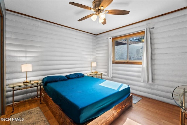 bedroom with hardwood / wood-style flooring, rustic walls, and ceiling fan