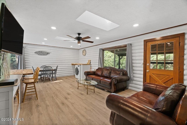 living room with a textured ceiling, log walls, a skylight, light wood-type flooring, and ceiling fan