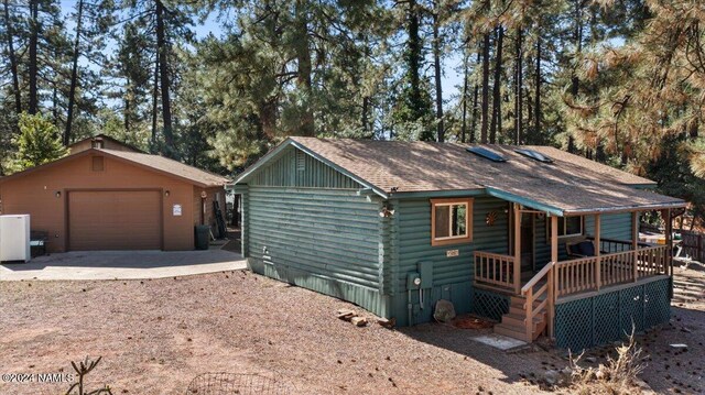 view of front of home featuring a garage, covered porch, and an outbuilding