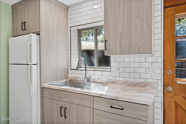 kitchen featuring light brown cabinetry, sink, white refrigerator, and a healthy amount of sunlight