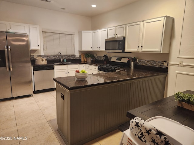 kitchen with a peninsula, appliances with stainless steel finishes, a sink, and white cabinets