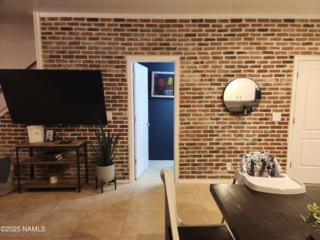 living area with light tile patterned floors and brick wall