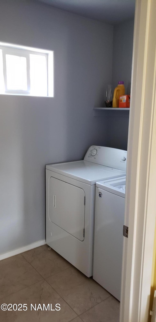 laundry area featuring light tile patterned floors, laundry area, washing machine and dryer, and baseboards