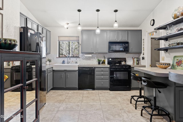 kitchen featuring pendant lighting, black appliances, lofted ceiling, sink, and gray cabinets