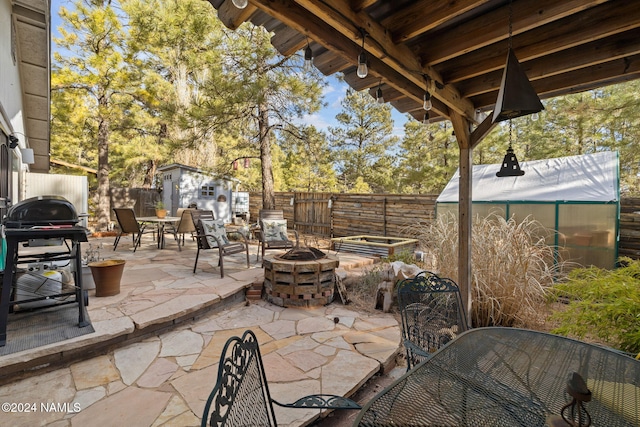 view of patio / terrace with a fire pit, a grill, and a storage unit