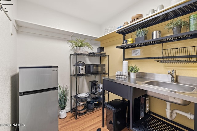 kitchen featuring sink, stainless steel counters, stainless steel refrigerator, and wood-type flooring