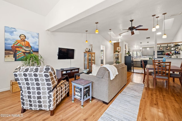 living room with vaulted ceiling, ceiling fan, and light hardwood / wood-style flooring