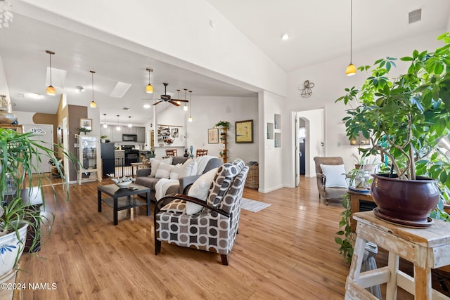 living room with ceiling fan, light hardwood / wood-style flooring, and high vaulted ceiling