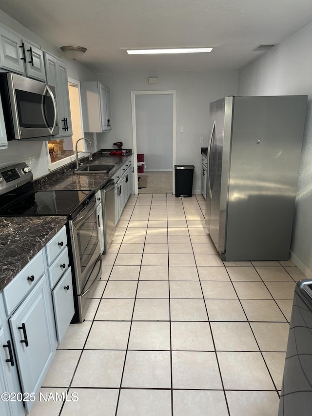 kitchen featuring sink, dark stone countertops, light tile patterned flooring, stainless steel appliances, and gray cabinets