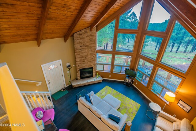 unfurnished living room with beamed ceiling, a fireplace, wood ceiling, high vaulted ceiling, and dark colored carpet