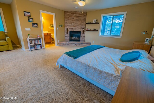 bedroom featuring a fireplace, carpet flooring, ensuite bathroom, and ceiling fan