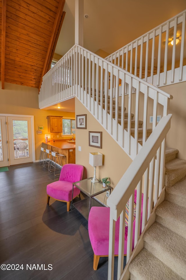 stairway featuring wood-type flooring, wooden ceiling, and high vaulted ceiling